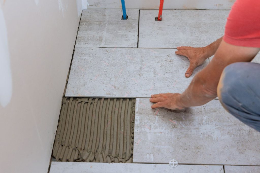 worker installing ceramic floor tiles
