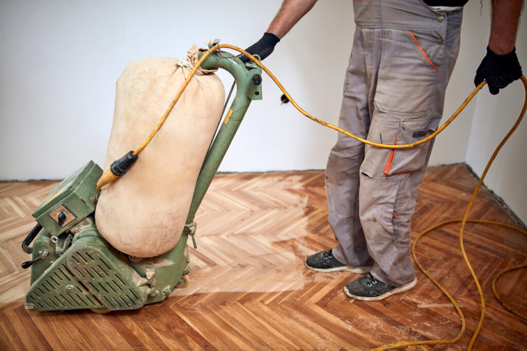 repairman sanding wood flooring