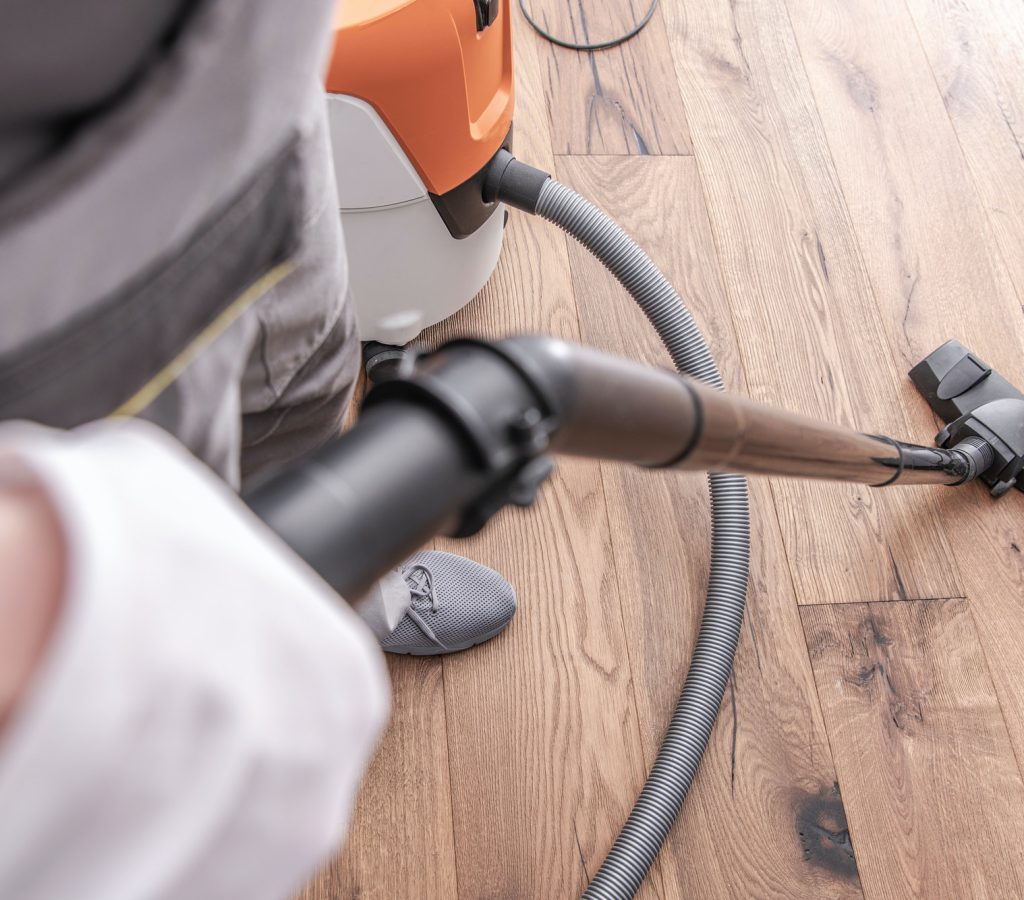 male worker vacuuming hardwood flooring